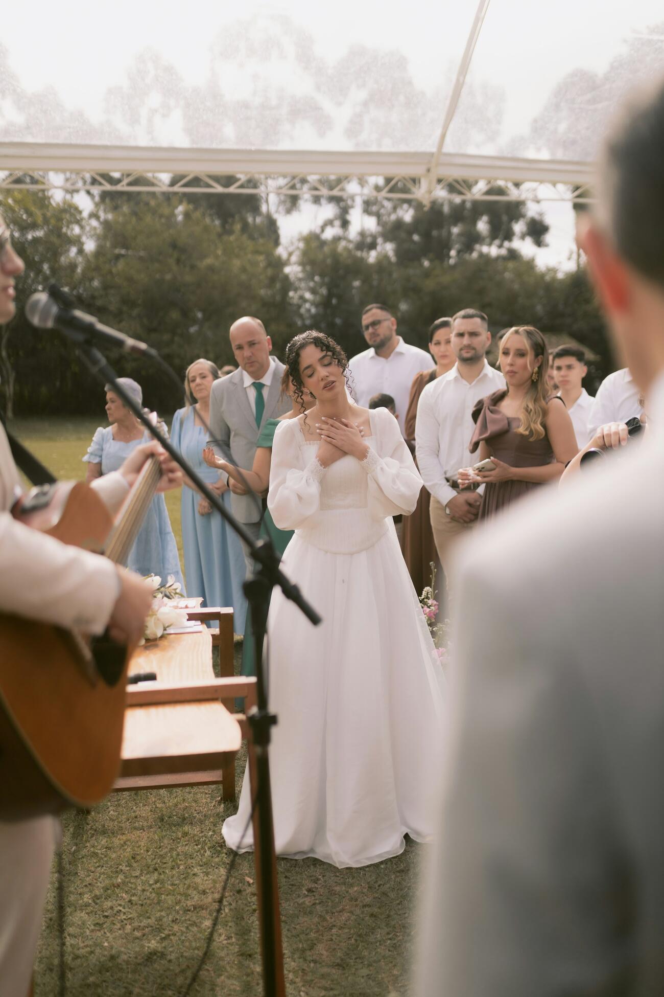 Bride standing with guests during outdoor wedding ceremony