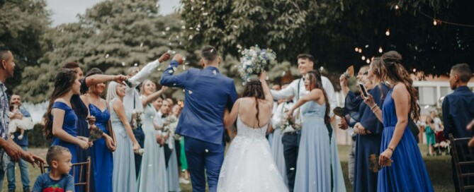 Bride and groom walking through cheering guests at outdoor wedding