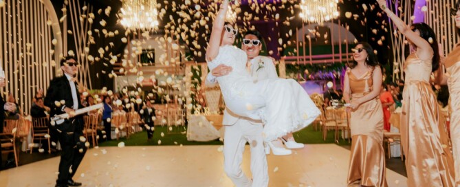 A newly married couple joyfully walks through a shower of colorful confetti, celebrating their wedding day