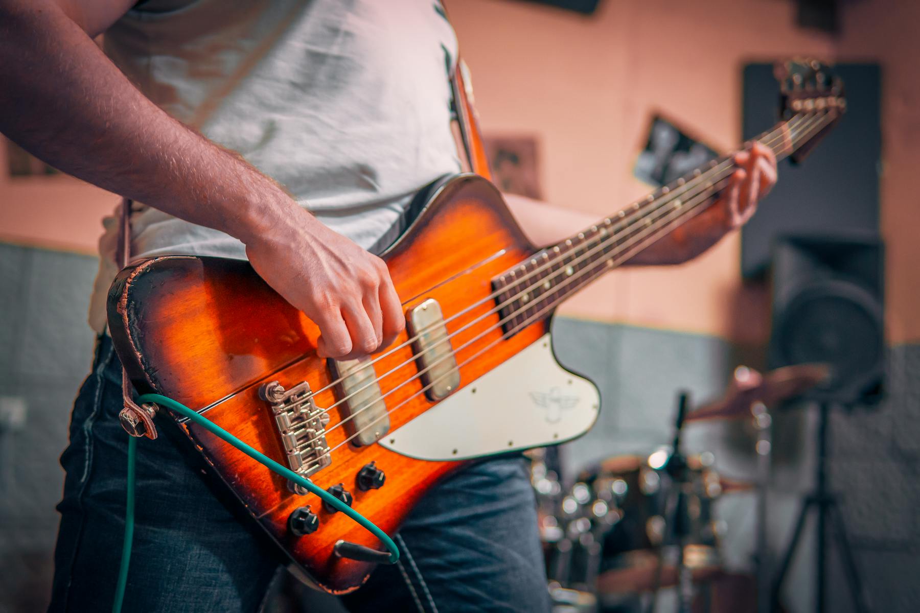 A man playing an electric bass guitar in a music studio, surrounded by sound equipment and musical instruments