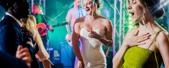 Bride and guests dancing with live band and colorful lights