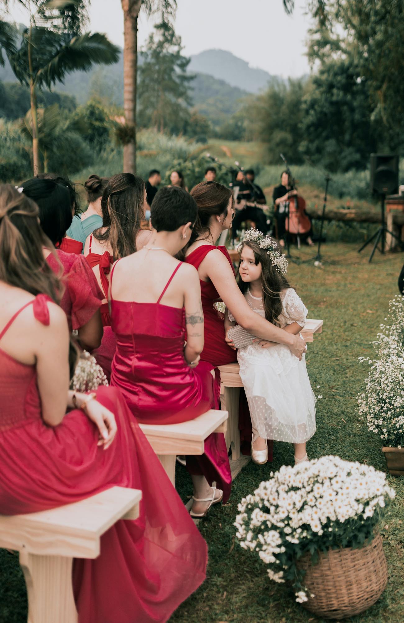 Guests sitting on a bench on a wedding ceremony with quartet band in front