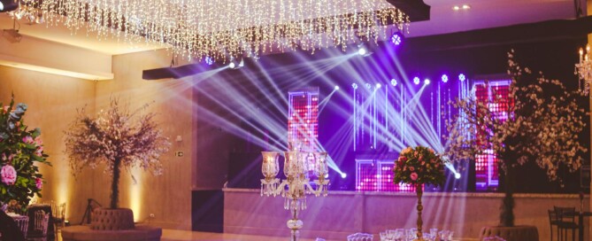 Elegant indoor wedding venue with stage lighting and decorated tables